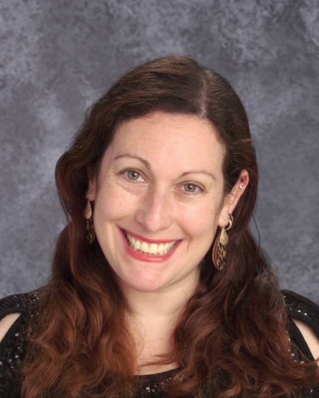 Woman with long black hair and a bright smile with a grey background