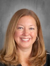 A smiling woman with long hair poses for the camera, radiating joy and confidence.