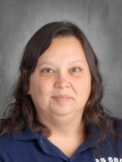 A woman dressed in a blue polo shirt, showcasing her black hair, exuding a professional demeanor.