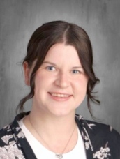 A woman wearing a floral shirt paired with a black cardigan.