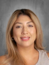 A woman with blonde hair wearing a white tank top smiling.