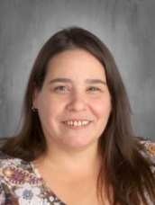 A woman with long hair in a vibrant floral shirt.