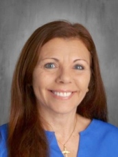 A woman with flowing red hair dressed in a blue shirt, exuding confidence.