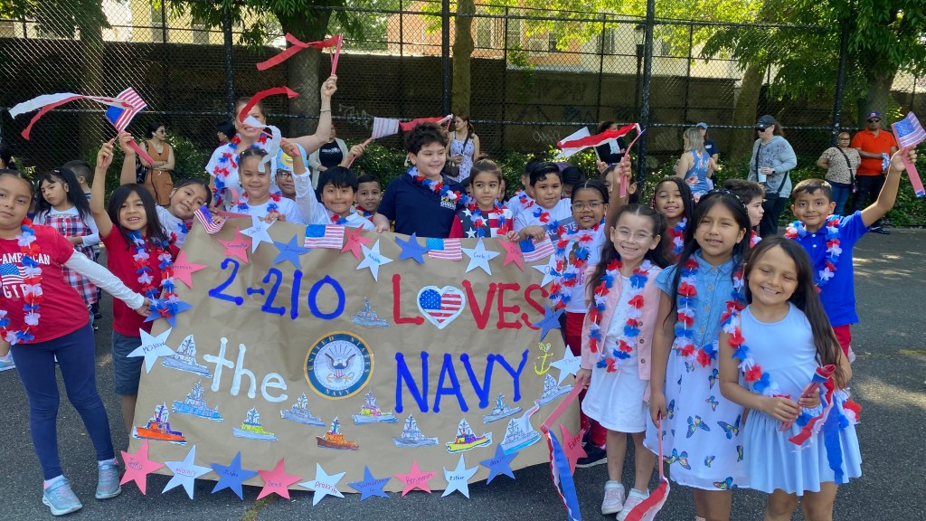 A group of happy children holding a sign that reads "we love the navy". .